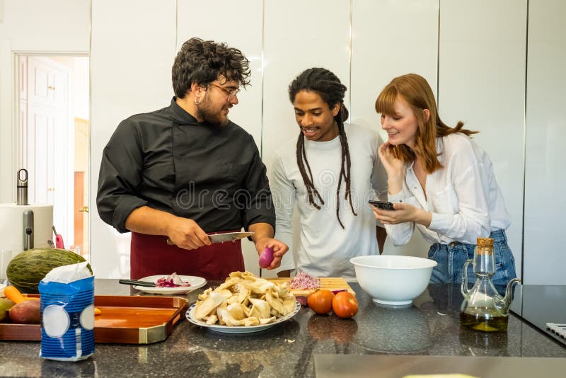 Chef-kok die een jong paar van verschillende rassen onderwijzen hoe te koken stock foto Chef-kok die een jong paar van verschillende rassen onderwijzen hoe te koken stock foto