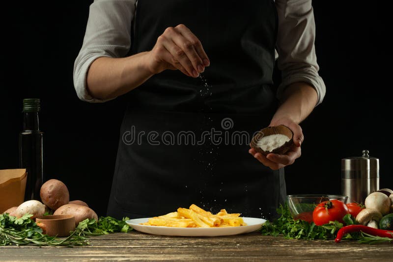Chef-kok die frieten klaar, op de achtergrond met groenten zouten Kokend smakelijk maar schadelijk voedsel Achtergrond voor ontwe