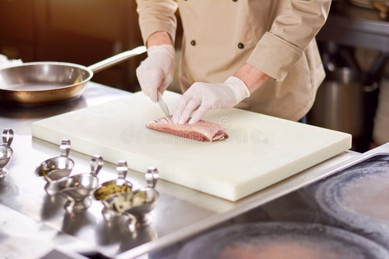 Chef-kok die het vlees aan boord snijden royalty-vrije stock afbeelding Chef-kok die het vlees aan boord snijden royalty-vrije stock afbeelding