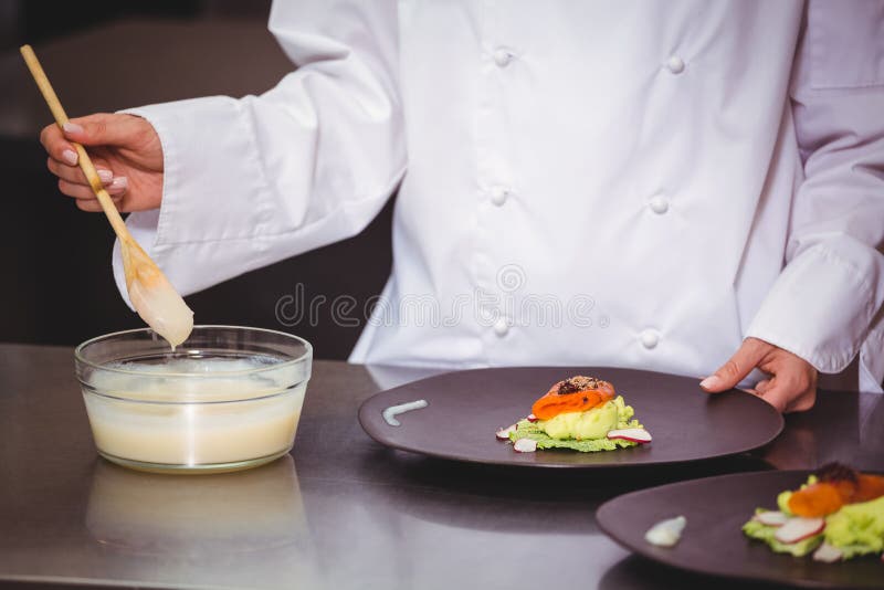 Chef-kok die saus op een schotel zetten stock afbeelding Chef-kok die saus op een schotel zetten stock afbeelding
