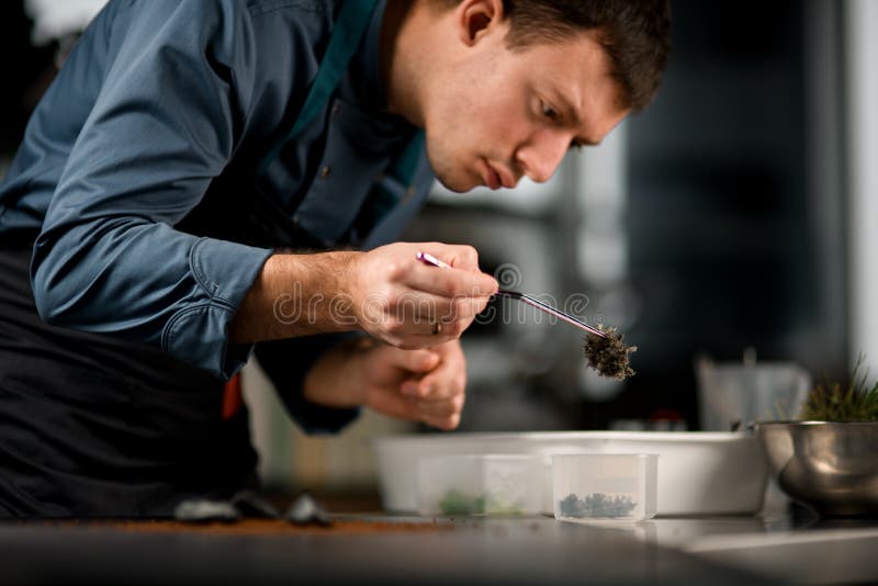 Chef Mâle Tenant Des Pincettes Avec L'ingrédient Pour Préparer Le