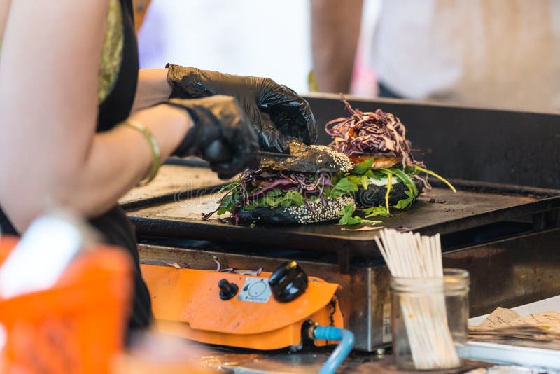 Chef making beef burgers outdoor on open kitchen international food festival event.