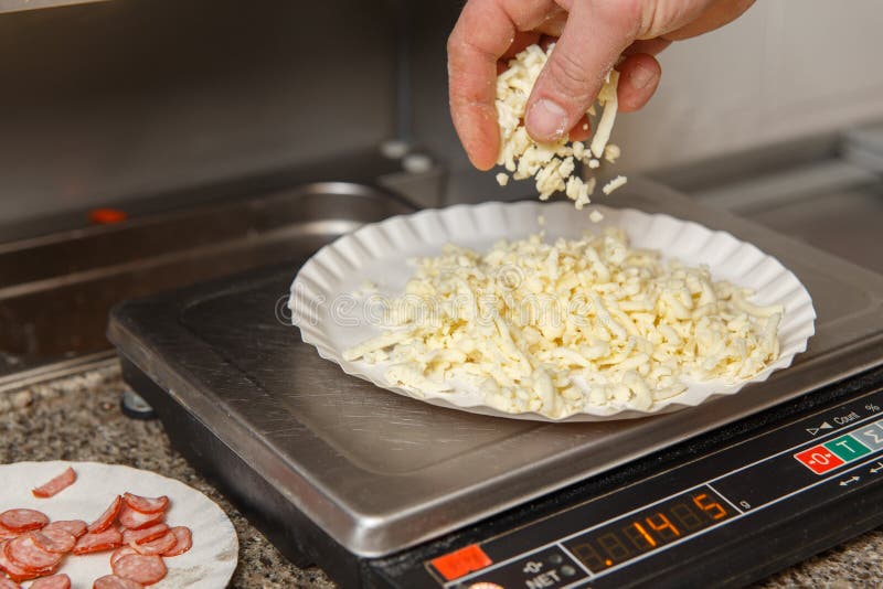The Chef Measures on the Scales the Required Amount of Cheese for Pizza