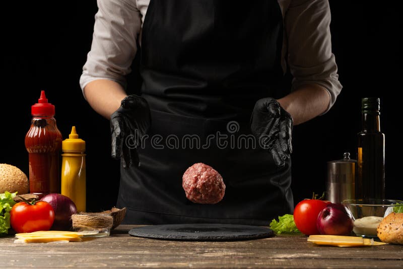 The chef prepares the cutlet with fresh ground beef, the ingredients on the background, cooking a delicious burger. Recipe book