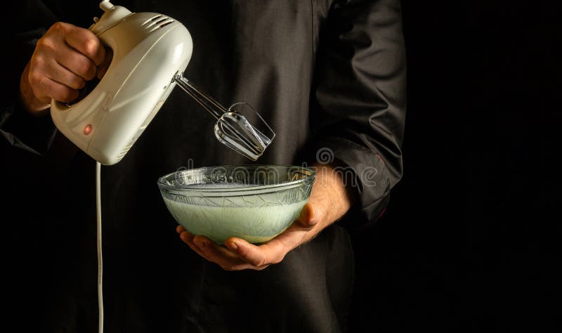 Preparing milkshake and fruit with an electric hand mixer. Refreshing drink  by the hands of the chef in the kitchen Stock Photo