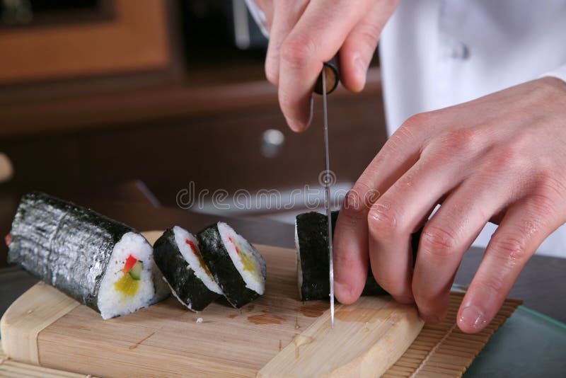 Chef Preparing Sushi-4. Close up of a Japanese chef slicing a fresh sushi wrap stock photography
