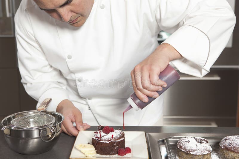 Chef Puts Finishing Touches On Chocolate Cake At Kitchen Counter