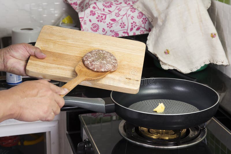 Chef putting beef Burger cooking in the pan royalty free stock photos