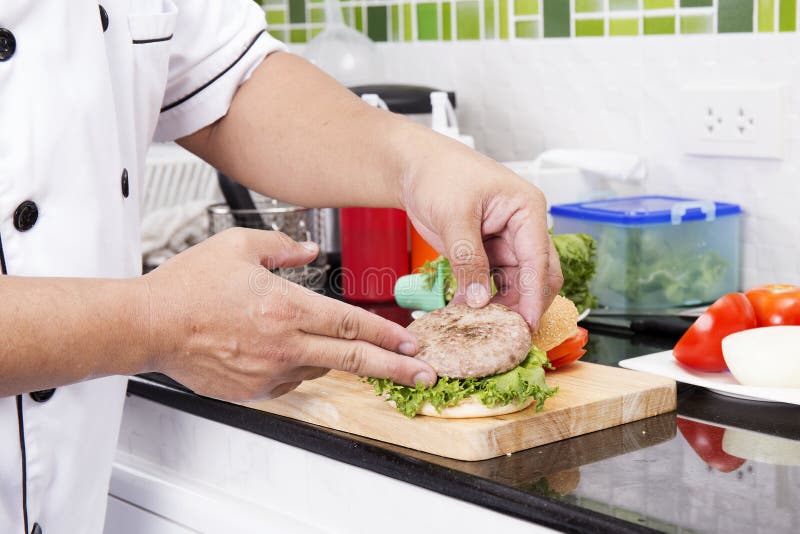 Chef putting beef hamburger on the bun royalty free stock photos