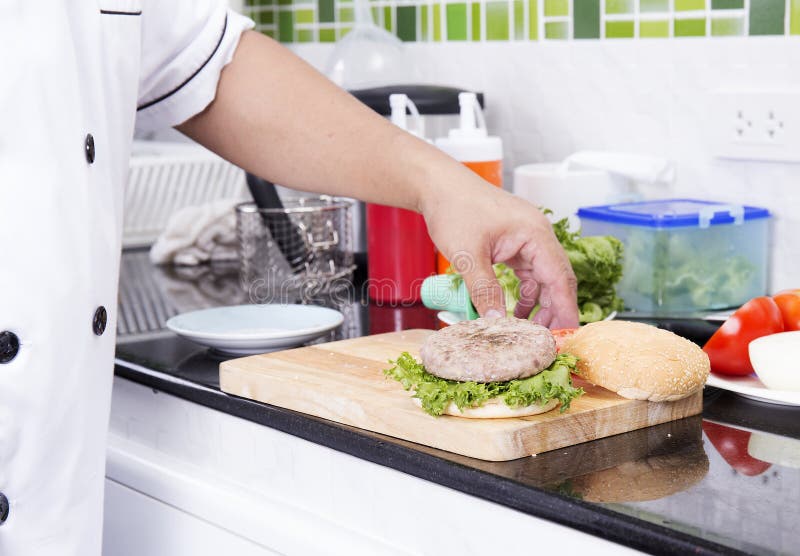 Chef putting beef hamburger on the bun royalty free stock photo