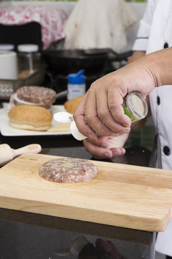 Chef putting pepper to beef burger / royalty free stock photography