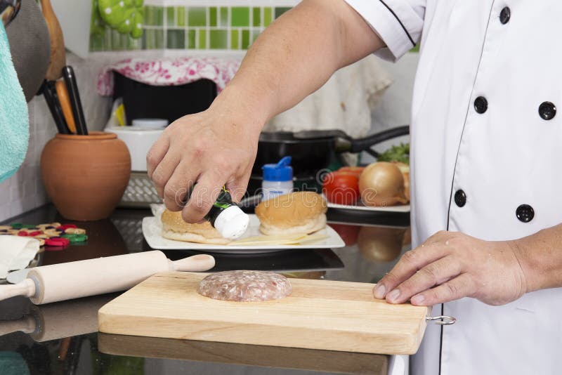 Chef putting pepper to beef burger royalty free stock photos
