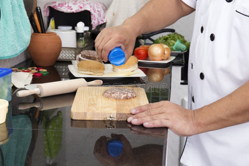Chef putting salt on to raw beef Burger royalty free stock images