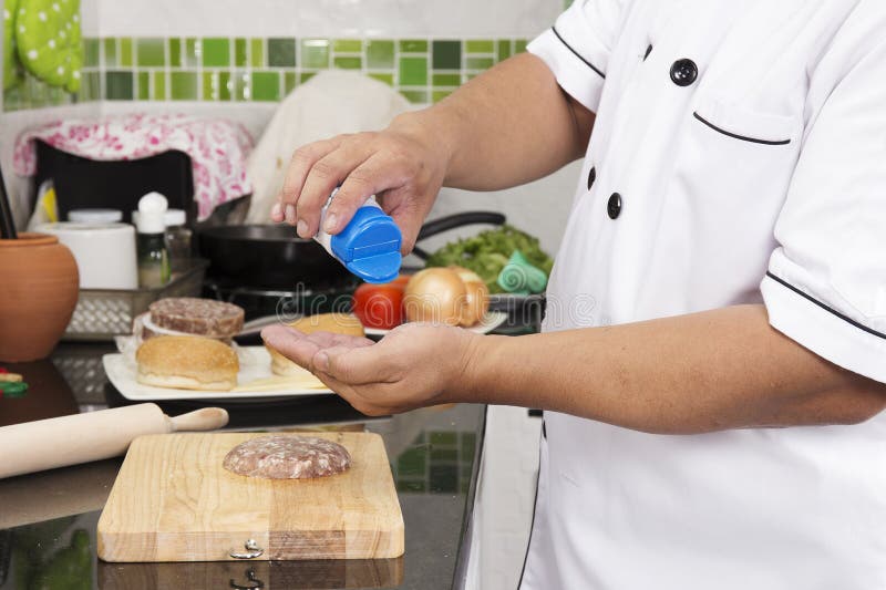 Chef putting salt on to raw beef Burger stock image