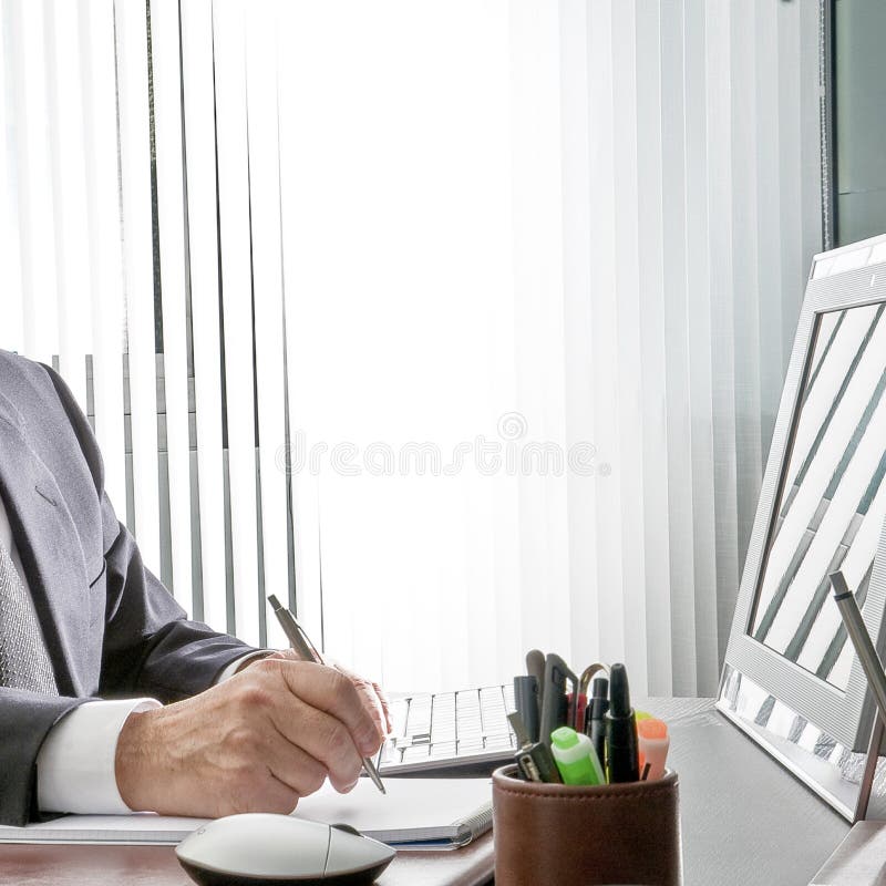 Chef på arbete Den sakkunniga handen av en affärsman som sitter på hans skrivbord, rymmer han pennan framme av hans datorbildskär arkivfoto Chef på arbete Den sakkunniga handen av en affärsman som sitter på hans skrivbord, rymmer han pennan framme av hans datorbildskär arkivfoto