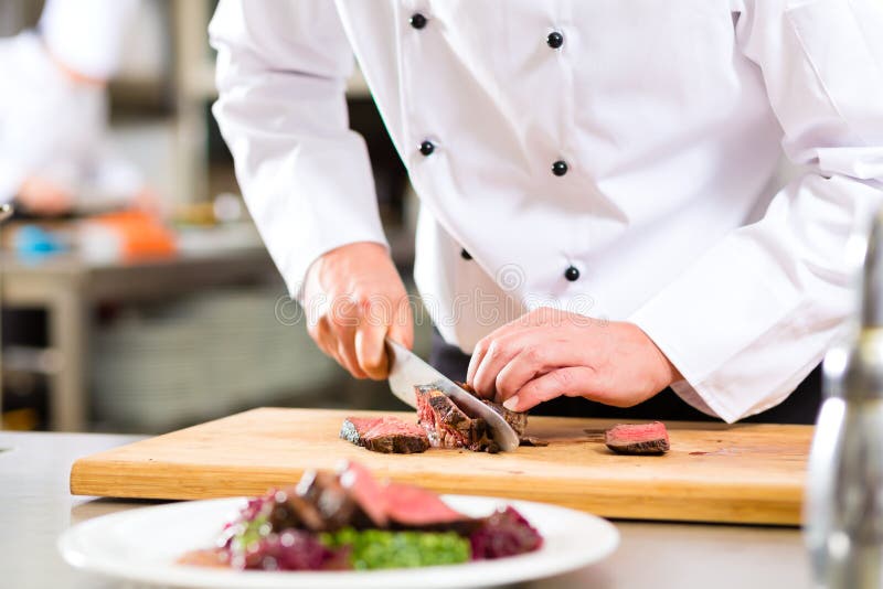 Šéfkuchař v hotelu nebo restaurace kuchyně vaření, pouze rukou, je řezání maso nebo steak pro jídlo na talíři.