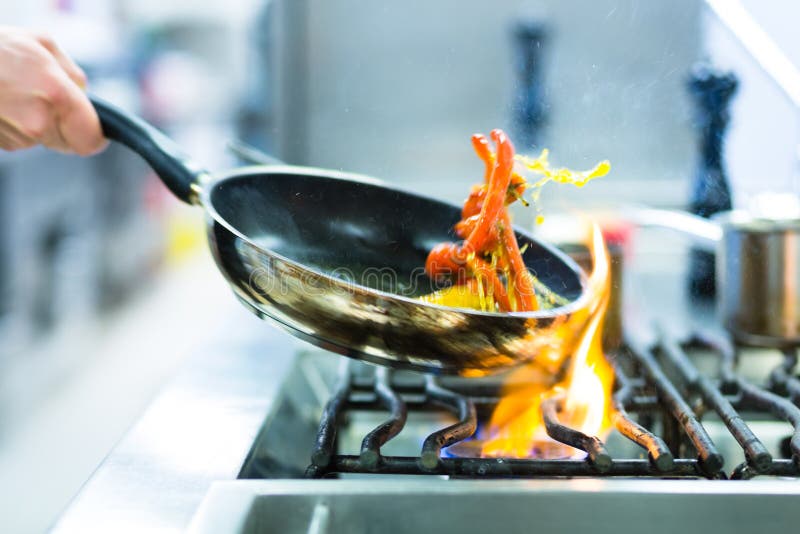 Cocinero en un restaurante La cocina sobre el cocina sartén, hacer flambear sobre el comida.