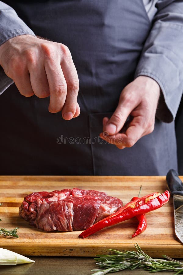 Chef seasoning rib eye steak on wooden board at restaurant kitch stock image Chef seasoning rib eye steak on wooden board at restaurant kitch stock image