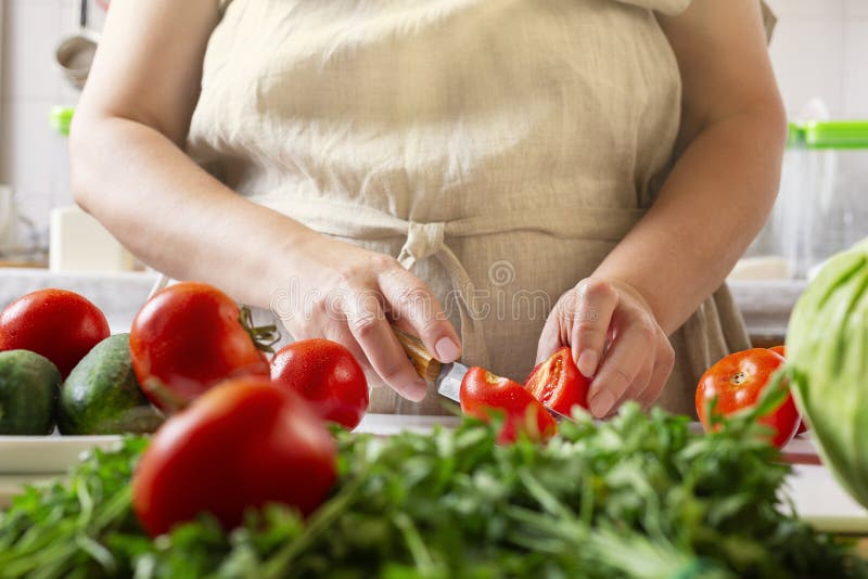 Chef Slicing Tomato Using Knife on the Table in Restaurant. Process of Cutting and Preparation