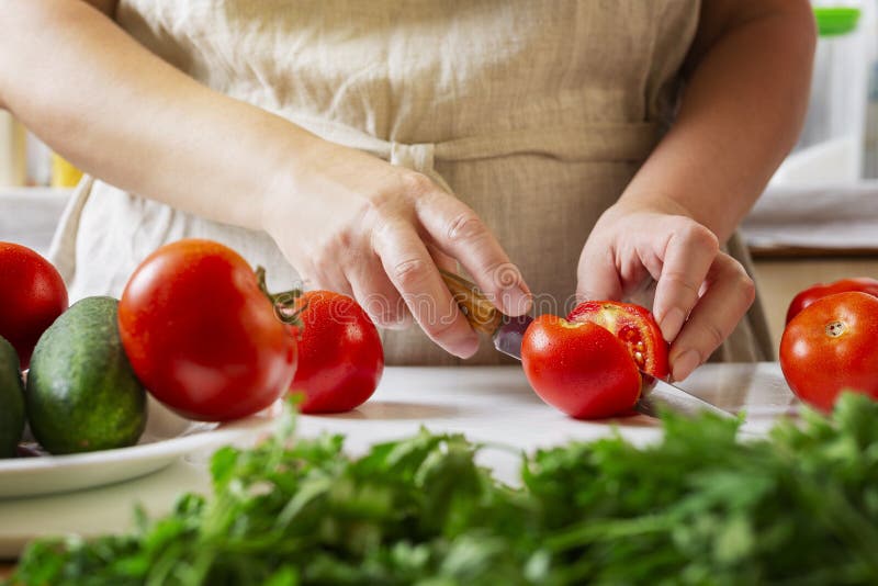 Chef Slicing Tomato Using Knife on the Table in Restaurant. Process of Cutting and Preparation