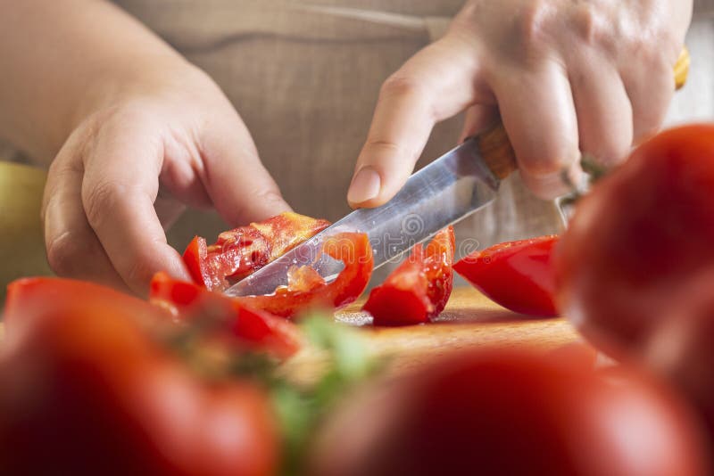 Chef Slicing Tomato Using Knife on the Table in Restaurant. Process of Cutting and Preparation