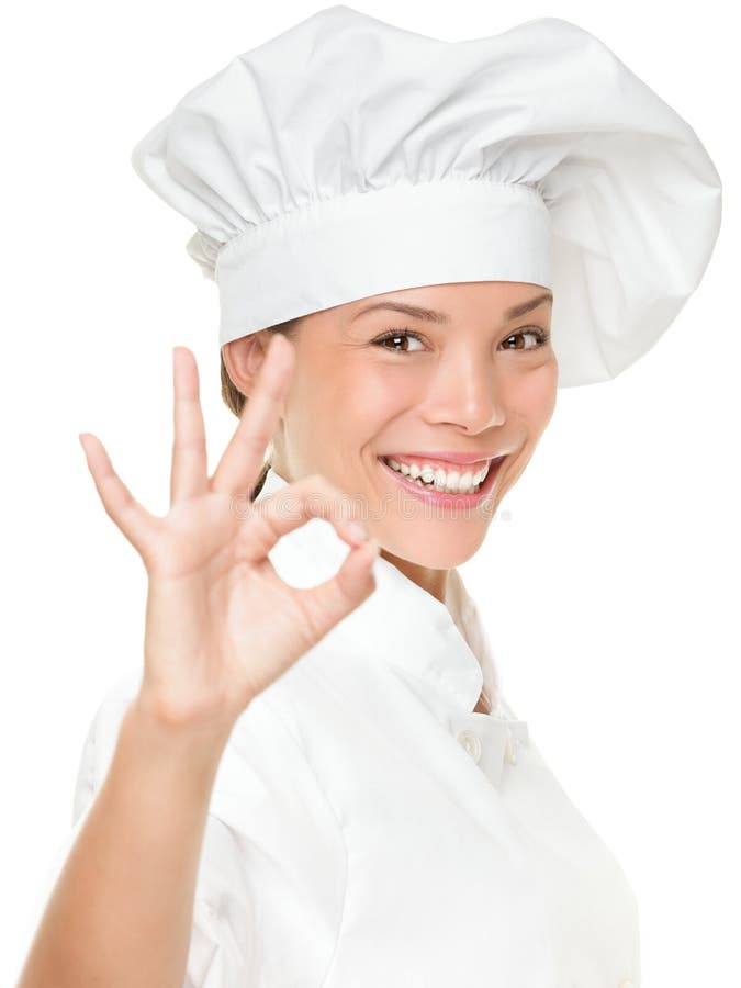 Chef baker or cook showing ok hand sign for perfection. Woman chef smiling happy and proud. Portrait of female cook wearing chefs hat isolated on white background. Mixed race Asian Caucasian female model. Chef baker or cook showing ok hand sign for perfection. Woman chef smiling happy and proud. Portrait of female cook wearing chefs hat isolated on white background. Mixed race Asian Caucasian female model.