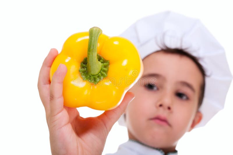 Chefe do rapaz pequeno que guarda a paprika amarela suculenta imagens de stock royalty free Chefe do rapaz pequeno que guarda a paprika amarela suculenta imagens de stock royalty free