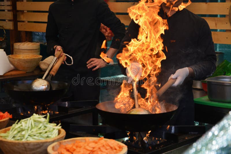 Chefs faisant cuire avec la flamme dans une poêle image libre de droits Chefs faisant cuire avec la flamme dans une poêle image libre de droits