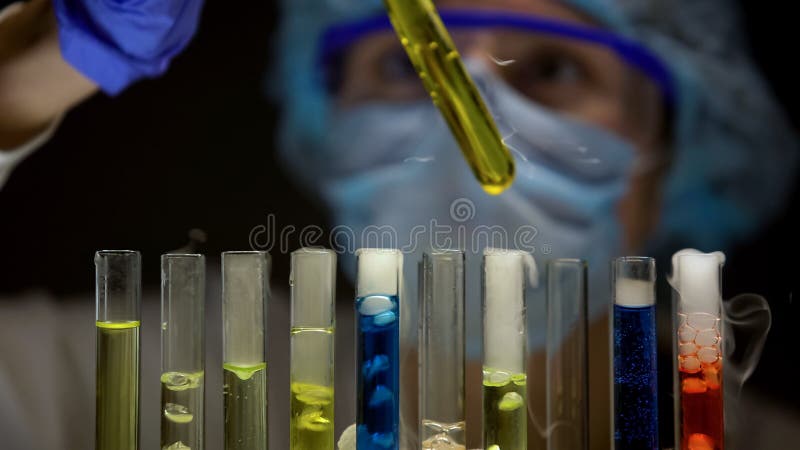Chemicus die sediment in buis met gele vloeistof, substanties controleren die rook uitzenden stock afbeelding Chemicus die sediment in buis met gele vloeistof, substanties controleren die rook uitzenden stock afbeelding
