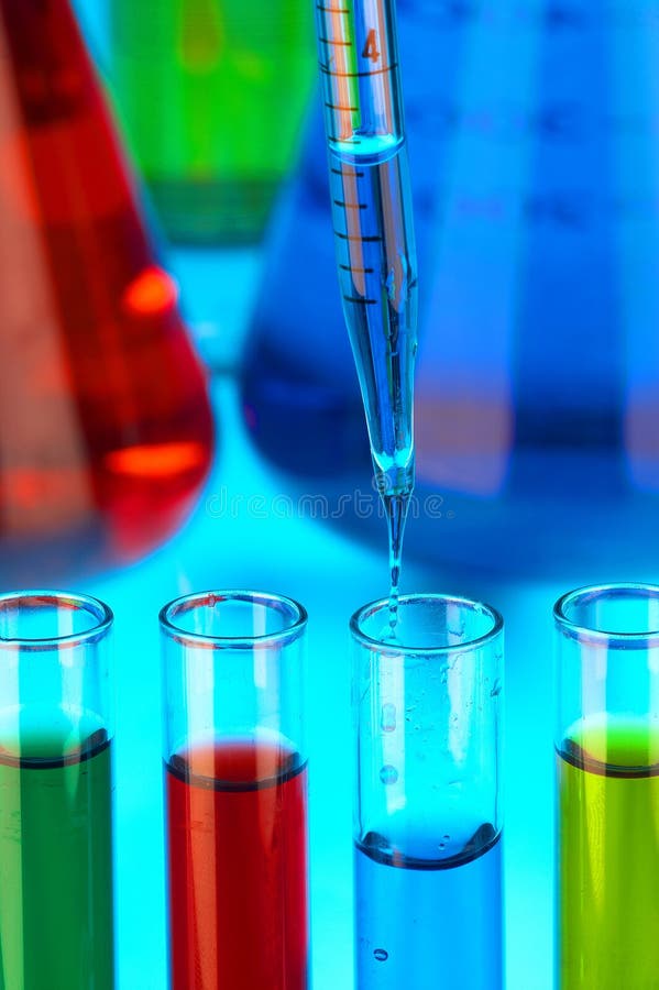 Many different coloured chemical solutions in laboratory glasses with pipettes on blue background. Many different coloured chemical solutions in laboratory glasses with pipettes on blue background