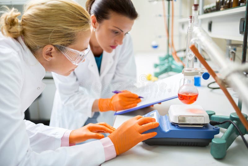Chemische technici die aan experiment in laboratorium werken stock afbeelding Chemische technici die aan experiment in laboratorium werken stock afbeelding