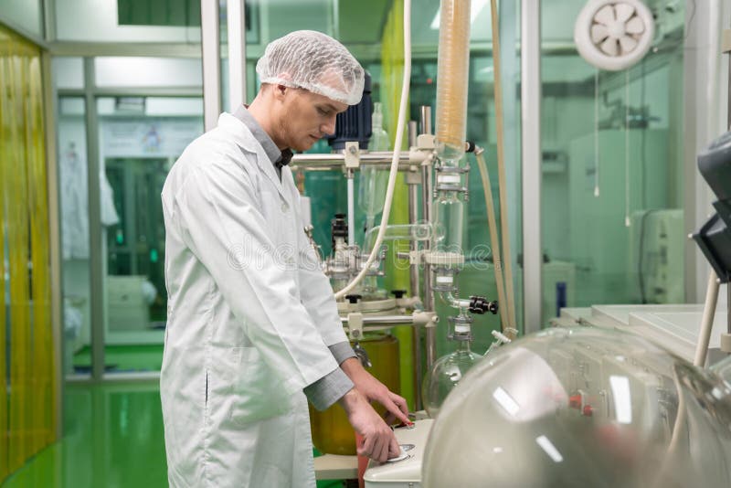 Scientist apothecary extract using cannabis extraction machine in laboratory.