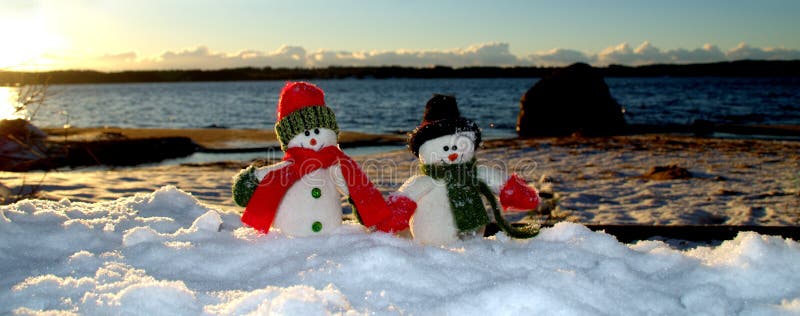 Cherful snowmans som promenerar stranden i snön arkivfoto Cherful snowmans som promenerar stranden i snön arkivfoto