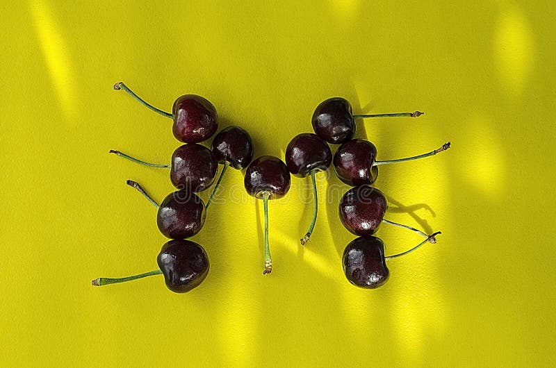 Cherry berries on a bright yellow background in the form of the letter M with sun highlights royalty free stock image Cherry berries on a bright yellow background in the form of the letter M with sun highlights royalty free stock image