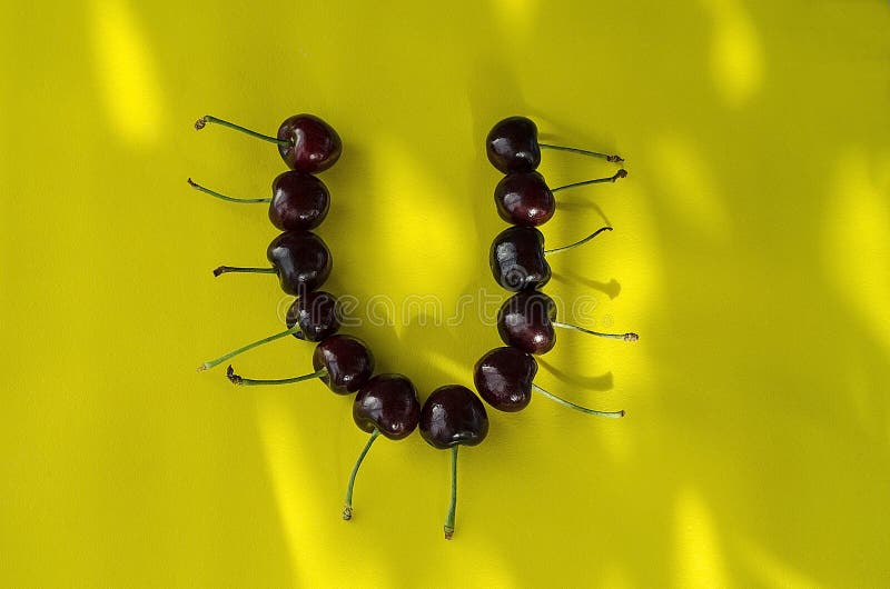 Cherry berries on a bright yellow background in the form of the letter U with sun highlights stock image Cherry berries on a bright yellow background in the form of the letter U with sun highlights stock image