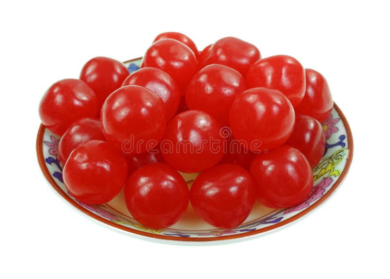 A group of shiny red cherry flavored candy balls in dish. A group of shiny red cherry flavored candy balls in dish.
