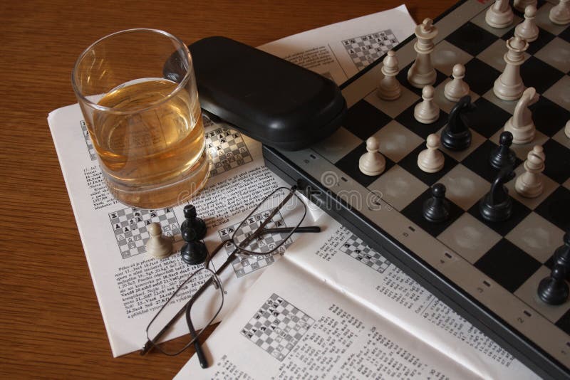 Focused man sipping alcoholic beverage while thinking about next chess move.  Stock Photo by DC_Studio