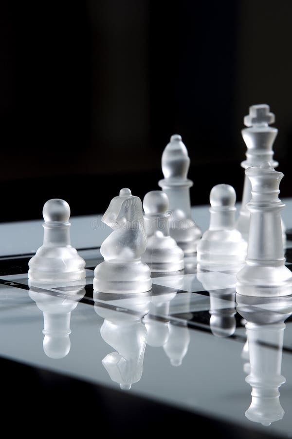 Chess. Glass chess pieces on board and dark background Chess. Glass chess pieces on board and dark background