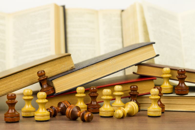 Chess pieces and books on a wooden table.