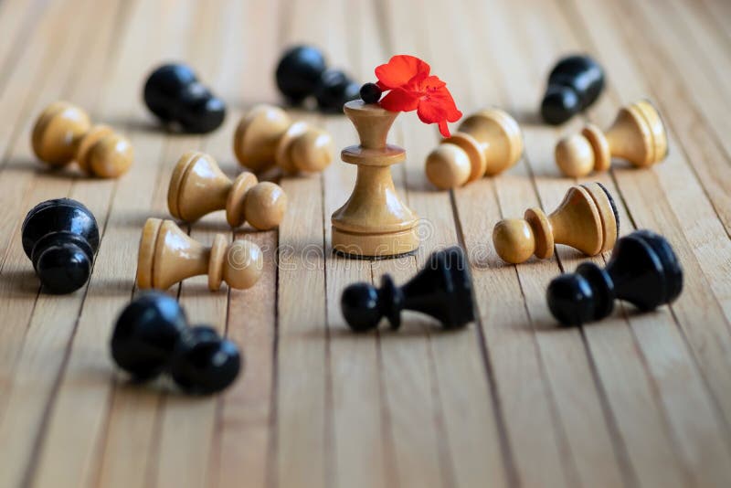 Chess pieces pawns lie bowing before the figure of the Queen with the red geranium flower. Abstract concept of social status