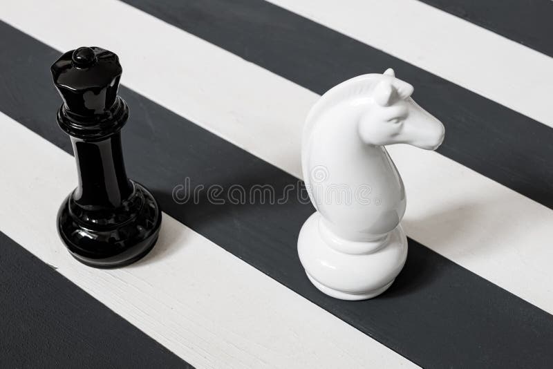 Chess pieces on a striped surface. the stripes are black and white. knight and queen stock photo Chess pieces on a striped surface. the stripes are black and white. knight and queen stock photo