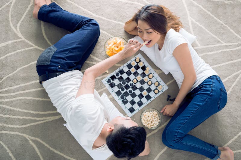 young couple playing chess while sitting at table at home - Unpacked