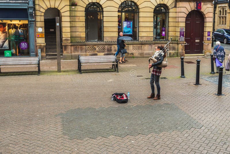 CHESTER ENGLAND - MARS 8TH, 2019: Kvinnliga säckpipe- lekar för en Busker i Chester royaltyfri bild CHESTER ENGLAND - MARS 8TH, 2019: Kvinnliga säckpipe- lekar för en Busker i Chester royaltyfri bild