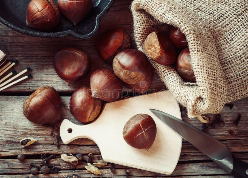 Chestnuts ready to roasting and frying pan on rustic kitchen tab