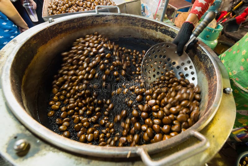 Chestnuts roasted with coffee beans on the fire from a street vendor with spin fry pan. Group of blurry edible ripe chestnuts due royalty free stock photos Chestnuts roasted with coffee beans on the fire from a street vendor with spin fry pan. Group of blurry edible ripe chestnuts due royalty free stock photos