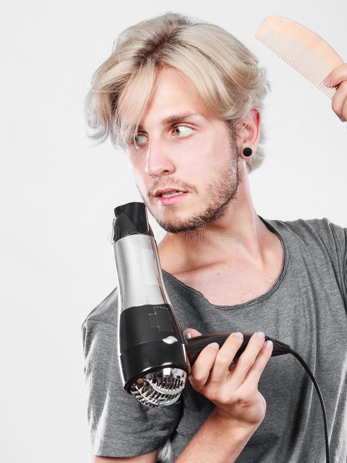 Cheveux de séchage de jeune homme avec le hairdryer image stock Cheveux de séchage de jeune homme avec le hairdryer image stock