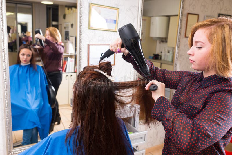 Cheveux séchants de styliste de client dans le salon image libre de droits Cheveux séchants de styliste de client dans le salon image libre de droits