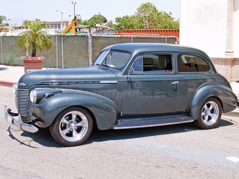 This is a restored 1939 Chevrolet sedan with some nice custom touches including a metallic gunmetal gray paint job and chrome spoke wheels.