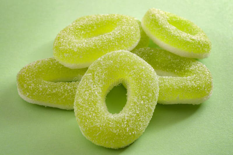 Chewy sweets and apple flavoured gummy candy concept with close up on sweet and sour green rings covered in granulated sugar