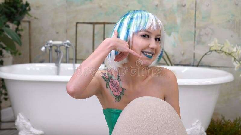 Chiamimi gesto dalla bella ragazza in parrucca nel bagno